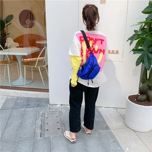 Blue nylon kids crossbody chest bag shown worn as a backpack in a street style view