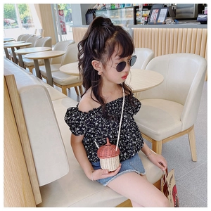 Detailed view of child wearing acorn-shaped woven straw crossbody bag in a cafe