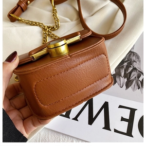 Dettaglio della mini borsa marrone con cuciture rifinite e fibbia in metallo dorato