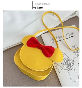 Detail view of a yellow toddler crossbody bag with a red bow and cute mouse ears