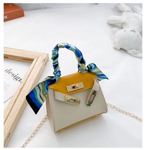 Dettaglio della mini borsa in pelle bicolore con manico in seta e tracolla dorata