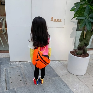 Outdoor shot of bright orange nylon kids chest bag with multiple zippers and adjustable strap