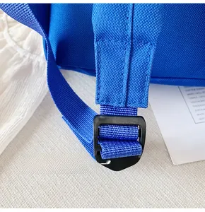 Detail of adjustable black plastic buckle and reinforced stitching on blue nylon backpack