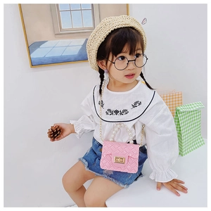 Pink jelly mini crossbody bag with pearl handle and metal chain shown on child model