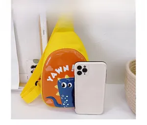 Size comparison of a yellow kids dinosaur chest bag next to a white smartphone