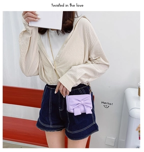 Detail view of purple mini bow crossbody bag with golden chain strap for young girls