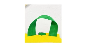 Vue détaillée d'un sac à dos en toile jaune avec des poignées tissées vertes