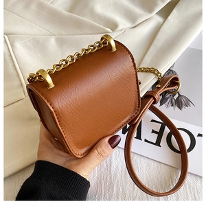 Dettaglio mini borsa a tracolla in pelle marrone caramello con manico a catena d'oro
