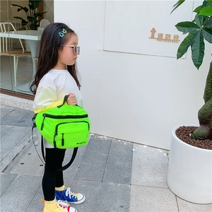 Detailed side view of fluorescent green nylon chest bag worn by a child in sunlight