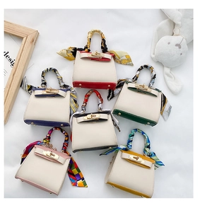 Dettaglio di sei mini borse a trapezio colorate con manici avvolti in foulard di seta