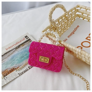 Detail of rose pink jelly bag with pearl handle and golden chain on white fabric