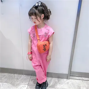 Vue détaillée du sac bandoulière orange pour enfant avec une combinaison rose et bottes