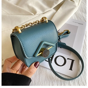 Dettaglio mini borsa a tracolla blu scuro con decorazione a V e catena dorata