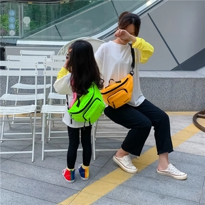 Outdoor shot showing adult and child versions of nylon crossbody bags in neon colors