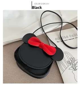 Detail of a mini round crossbody bag with cute black ears and a red bow for kids