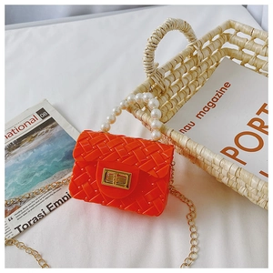 Detail view of orange jelly mini bag featuring pearl handle and woven texture design