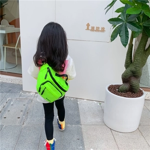 Detail of vibrant neon green kids chest bag with three zipper compartments and wide strap