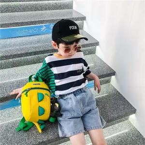 Détail d'un sac à dos dinosaure jaune avec un t-shirt rayé et un short en jean pour enfant