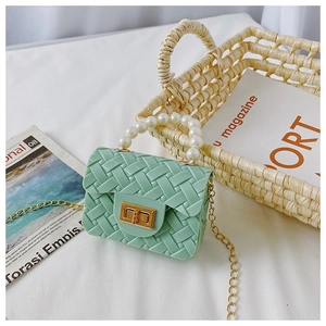 Detail of mint green jelly mini bag with woven texture, pearl handle and gold chain strap