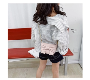 Pink girls' crossbody bag with large bow detail and gold chain strap on a child model