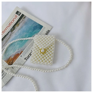 Detail of a white handmade pearl mini bag with a large gold-edged pearl buckle
