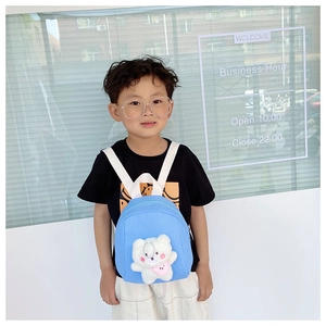 Blue kids backpack with a cute white plush bear toy shown on a young boy model