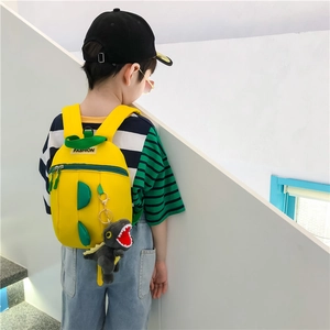 Vue latérale d'un enfant portant un sac à dos dinosaure jaune avec peluche décorative