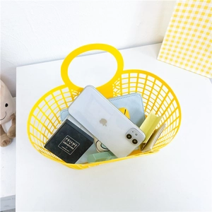 Detail of yellow hollow plastic beach basket with woven texture and round handles