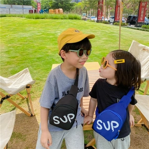Close-up of kids chest bags in black and blue with SUP print on outdoor lawn