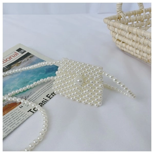 Macro shot of handcrafted white faux pearl woven mini bag with elegant flap design