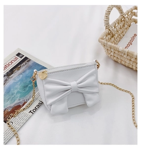 Detail of white PU leather crossbody bag featuring a large bow and gold heart zipper