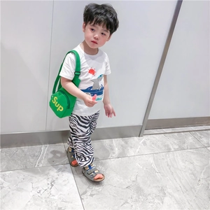 Détail d'un sac bandoulière vert pour enfant avec pantalon zébré et t-shirt blanc décontracté