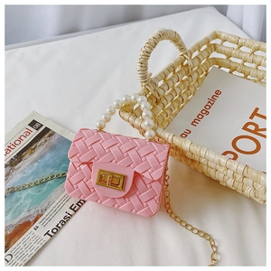 Close-up of pink jelly mini bag with pearl handle, woven texture and gold chain strap