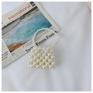 Detailed view of woven mini faux pearl handbag on a minimalist newspaper background