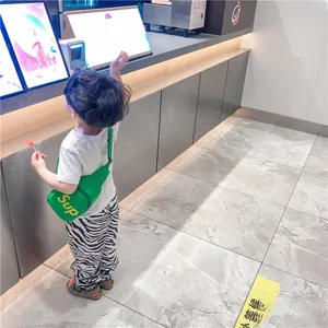 Détail d'un sac de poitrine vert pour enfants avec imprimé Sup sur un bambin