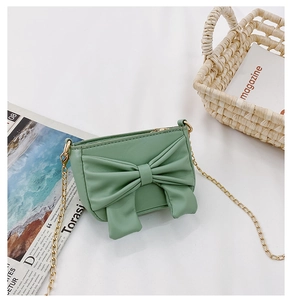Detail of light green mini crossbody bag with large bow and delicate gold chain strap