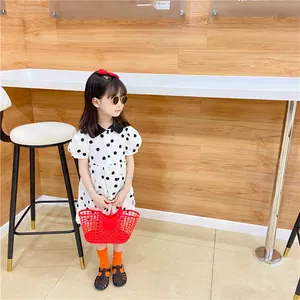 Detail shot of a white cotton dress with black polka dots and puff sleeves for girls