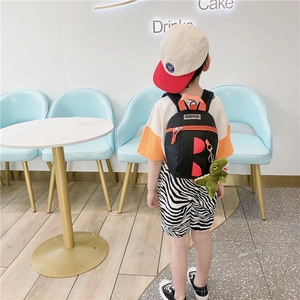 Détail d'un sac à dos dinosaure pour enfant en toile noire avec garniture rouge