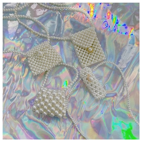 Detail view of handcrafted white pearl beaded mini bags with decorative floral metal clasps