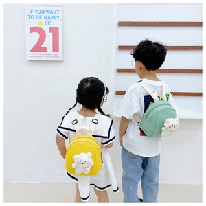 Rear view of children wearing cute yellow and green backpacks with plush bear pendants