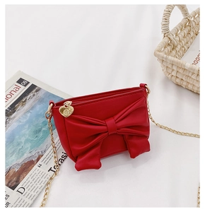 Detailed macro of a red bow mini crossbody bag featuring a golden heart zipper pendant
