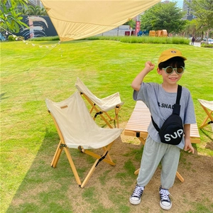 Full view of a boy wearing a black canvas crossbody bag with white SUP letter print