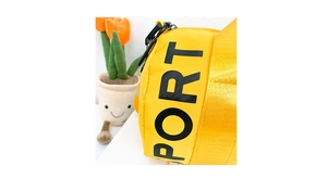 Close-up of bright yellow nylon sports bag featuring bold black PORT letter printing