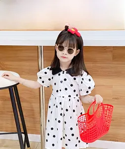 Detail of girl's polka dot dress with bubble sleeves and black collar in a studio setting