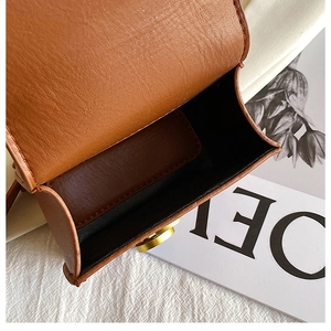 Dettaglio della mini borsa in pelle marrone con trama litchi e chiusura magnetica dorata