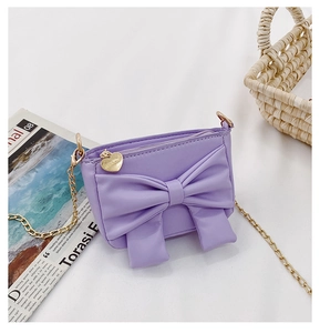 Detail of light purple girl purse with large bow, gold chain, and heart pendant