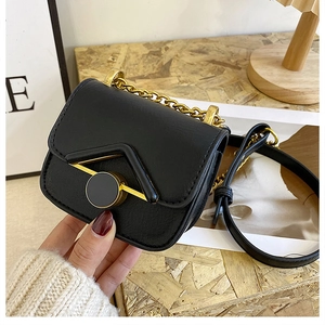 Dettaglio della mini borsa a tracolla nera con patta a V e catena in metallo dorato