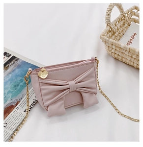 Close-up of pink crossbody bag with a large bow detail and golden heart zipper