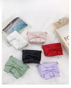 Close-up of mini bow crossbody bags in six vibrant colors with gold metal zipper details