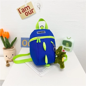 Détail du sac à dos dinosaure bleu avec piques vertes et pendentif en peluche
